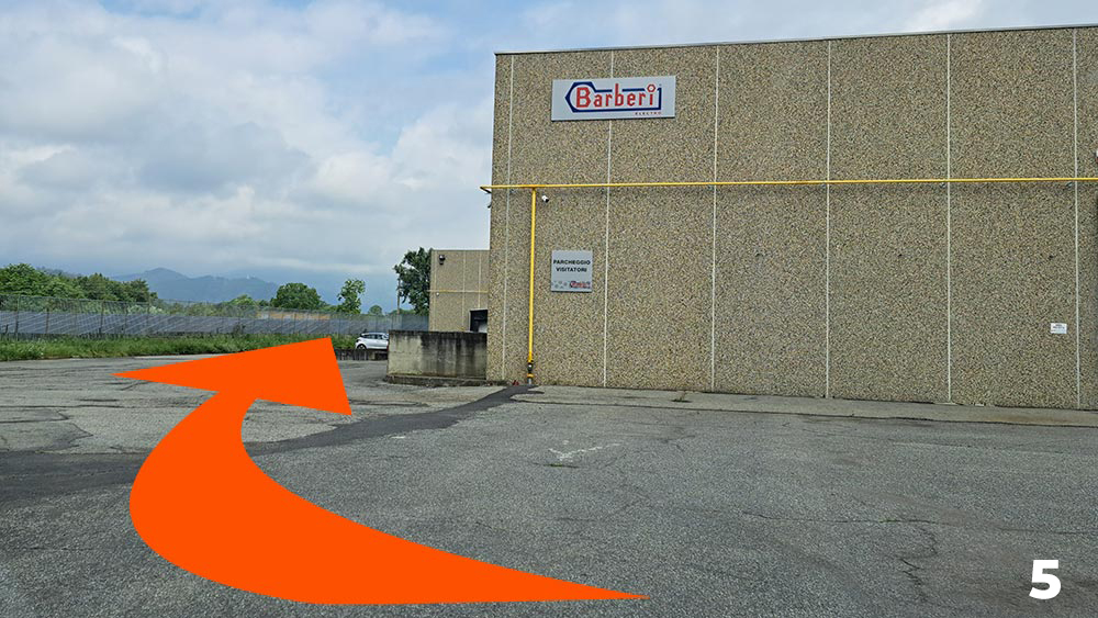 Once past the small bridge, turn left and follow the side of the warehouse.